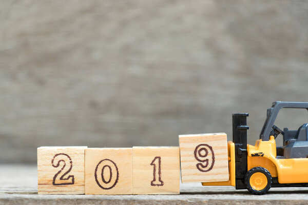 Игрушечная форточка держит букву 9, чтобы закончить слово 2019 на деревянном фоне
