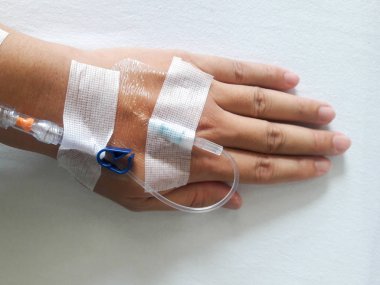 Beyaz kumaş arka plan üzerinde normal salin infüzyon tüp ile hasta el