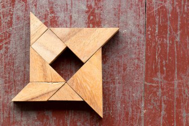Kırmızı eski ahşap arka plan üzerinde shuriken şeklinde bulmaca Tangram