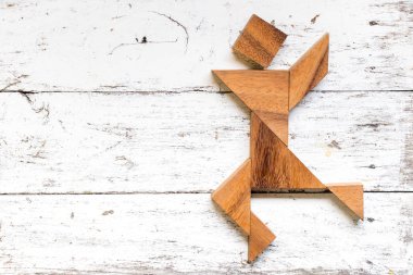 Tangram bulmacanın mutlu çalışan veya adam şekil eski beyaz ahşap arka plan üzerinde dans