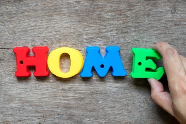 Word'de ev ahşap arka plan (rüya ev, mutlu aile kavramı mortgage kredi, mülkiyet yerine getirmek için el E tutun ile renkli plastik alfabesi)