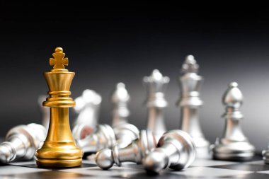 Altın Kral satranç parça başka bir gümüş takım ile yüz ve siyah arka plan (Şirket Stratejisi, iş zafer veya karar kavramı üzerine uzan piyon var.)