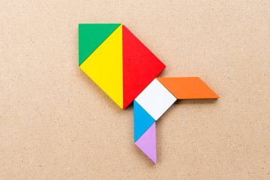 Renk tangram bulmacanın (kavram yeni deneyimi için başlangıç proje kadar ahşap arka plan üzerinde roket veya füze şeklinde)
