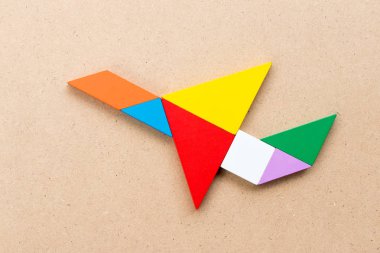 Uçak şekil ahşap arka plan üzerinde uçan renk tangram bulmacanın