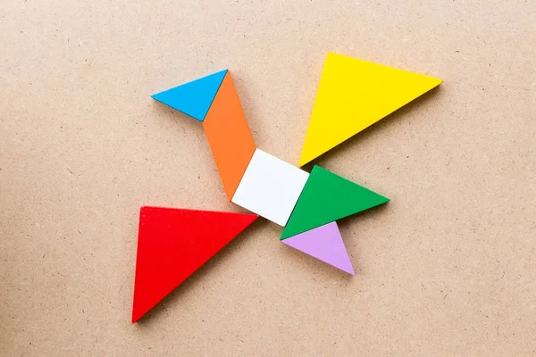 Kuş şekli ahşap arka plan üzerinde uçan renk tangram bulmacanın
