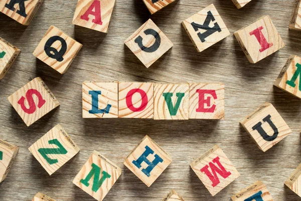 Letter block in word love with another on wood background