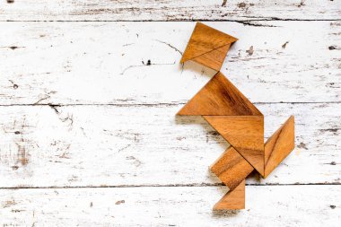 Eski Beyaz ahşap zemin üzerinde mutlu çalışan adam şeklinde bulmaca Tangram