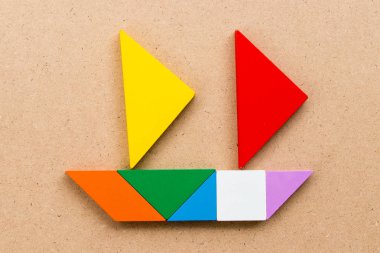 Tangram bulmacanın içinde yelken tekne şekli ahşap arka plan (konsept için Başlat iş veya yeni yolculuk üzerinde renk)