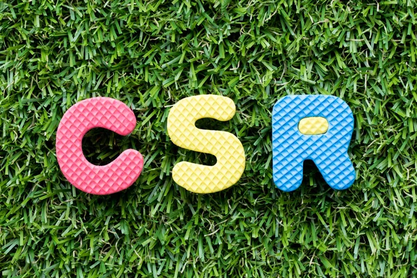 Color alphabet letter in word CSR (Abbbreviation of corporate social responsibility) on artificial green grass background