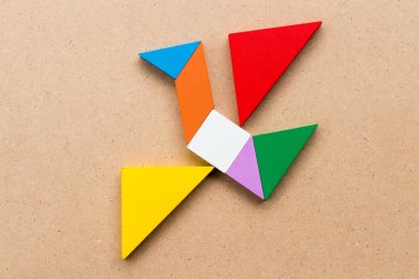 Kuş şekli ahşap arka plan üzerinde uçan renk tangram bulmacanın