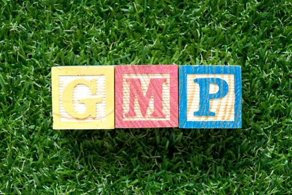 人工の緑の草の背景に関するワードで Gmp よい製造業練習の略 カラー ウッド ブロック — ストック写真