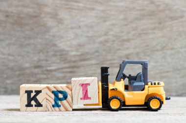 Oyuncak forklift tutun lette ben kelime KPI (kısaltma anahtar performans göstergesi) tamamlamak için ahşap arka plan üzerinde engellemek