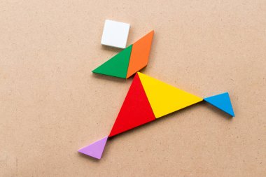 Tangram bulmacanın çalışan veya sevinç kişilerde şekil ahşap arka plan üzerinde renkli