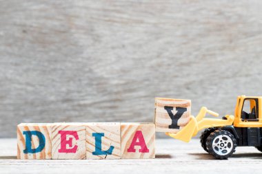 Oyuncak buldozer kelime gecikme ahşap arka plan üzerinde tamamlamak için mektup blok y tutun