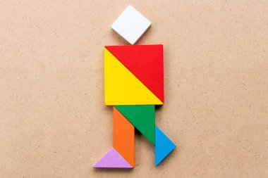 Tangram bulmacanın çalışan veya sevinç kişilerde şekil ahşap arka plan üzerinde renkli