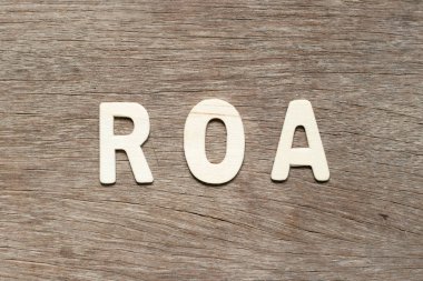 Alphabet letter in word ROA (Abbreviation of Return on assets) on wood background