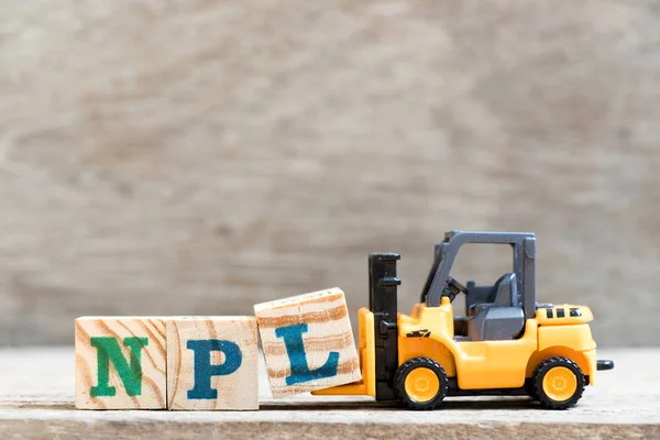 Oyuncak forklift tutun mektup blok L Word Npl (sigara gerçekleştirme kredi, Sigara-Patent edebiyat kısaltma) ahşap arka plan üzerinde