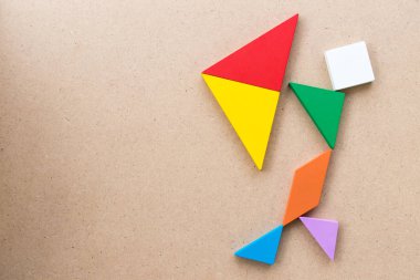Renk tangram bulmacanın Man tutun şemsiye şekli üzerinde ahşap arka plan (kavram olarak iş vardır kriz veya sorun)