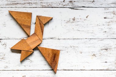 Eski Beyaz ahşap arka plan üzerinde kuş şekli uçan bulmaca Tangram