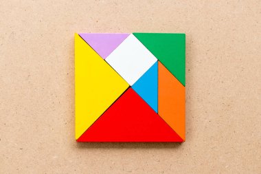 Renk tangram bulmacanın ahşap arka plan üzerinde kare şeklinde