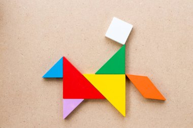 Renk tangram bulmacanın adam binmek at şeklinde ahşap arka plan üzerinde