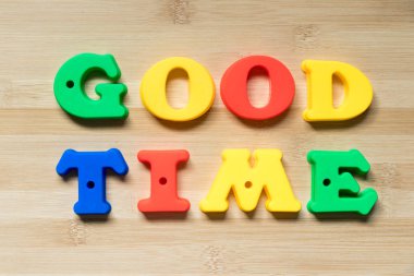 Kelime iyi zamanlı ahşap arka plan olarak renk plastik alfabesi