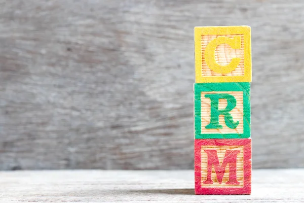 Color letter block in word CRM (Abbreviation of Customer Relationship Management) on wood background