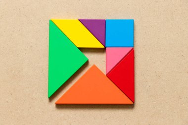 Renk tangram bulmacanın ok ahşap arka plan üzerinde kare şeklinde