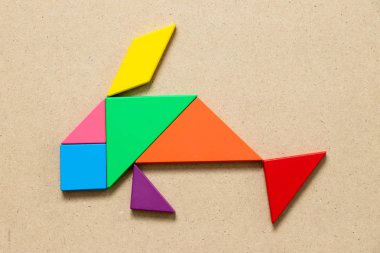 Ahşap arka plan üzerinde balık şekil yüzme içinde renk tangram bulmacanın