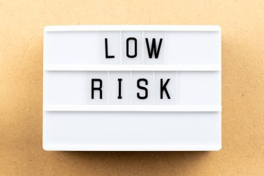 Ahşap arka plan üzerinde kelime düşük riskle ışık kutusu