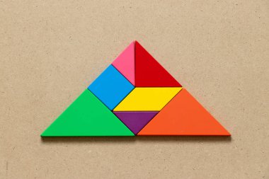 Ahşap arkaplanda üçgen şeklinde renk tangramı yap-bozu