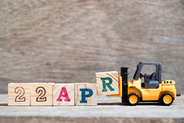 Ahşap arka plan (takvim tarihi 22 Nisan ayında konsepti üzerinde 22 Nisan kelime tamamlamak için oyuncak forklift tutun blok R)
