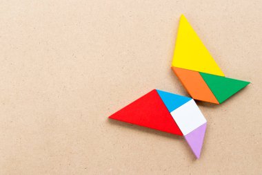 Renk tangram bulmacanın ahşap arka plan üzerinde kelebek şeklinde