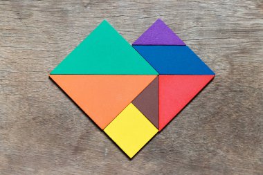 Renk tangram bulmacanın ahşap arka plan (sevgilisi için genel kavram ya da Sevgililer günü üzerinde kalp şeklinde)