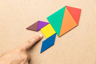Ahşap arka plan (Konsept başlangıç, yeni bir deneyim ya da iş için üste de el ile roket şeklinde renk tangram)