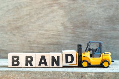 Oyuncak forklift tutun kelime marka ahşap arka plan üzerinde tamamlamak için mektup blok d