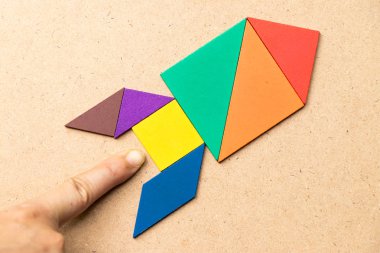 Ahşap arka plan (Konsept başlangıç, yeni bir deneyim ya da iş için üste de el ile roket şeklinde renk tangram)