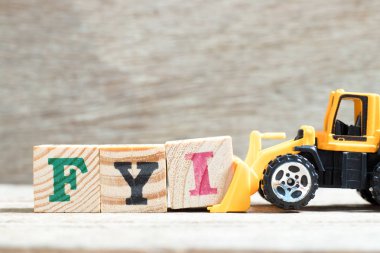 Oyuncak buldozer tutun mektup ben kelime Bilginize (kısaltma, bilgin) tamamlamak için ahşap arka plan üzerinde engellemek