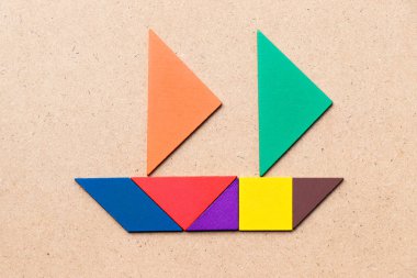 Ahşap zemin üzerinde yelkenli teknesi şeklindeki renk tangramı (Girişimci ya da iş kurma kavramı)