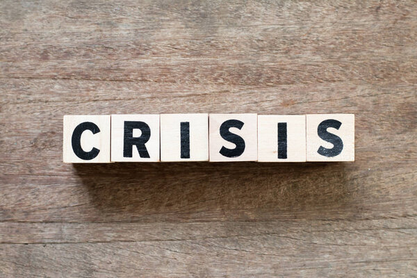 Letter block in word crisis on wood background