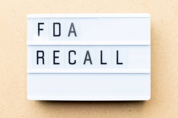 White lightbox with word fda recall on wood background