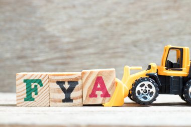 Oyuncak buldozer tutun kelime Fya (kısaltma-in için eylem veya dikkat) ahşap arka plan üzerinde tamamlamak için blok A harfi