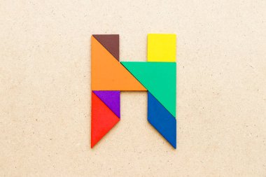 Ahşap arka plan üzerinde Alfabe harf H şeklinde bulmaca Tangram