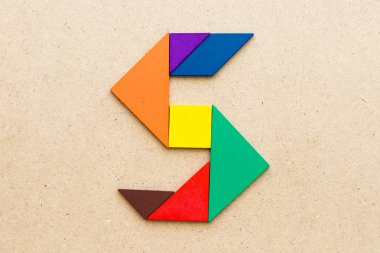 Ahşap arka plan üzerinde alfabe Harf S şeklinde bulmaca Tangram