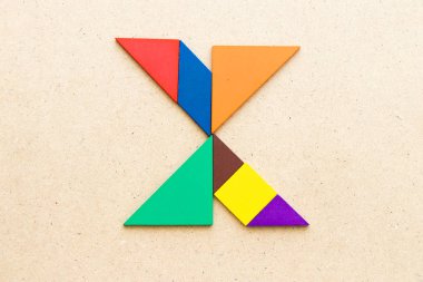 Ahşap arka plan üzerinde Alfabe harf X şeklinde bulmaca Tangram
