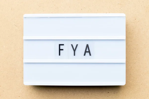 Lightbox branco com palavra FYA (abreviatura de Para sua ação ou atenção) sobre fundo de madeira — Fotografia de Stock