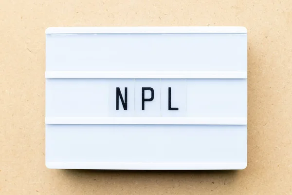 Biały lightbox z word Npl (Abbbreviation z Non wykonywania pożyczki, literatura Non-Patent) na tle drewna — Zdjęcie stockowe