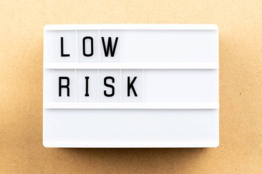 Ahşap arka plan üzerinde kelime düşük riskle ışık kutusu