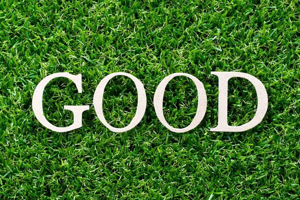 Carta de madeira em palavra boa no fundo de grama verde artificial — Fotografia de Stock