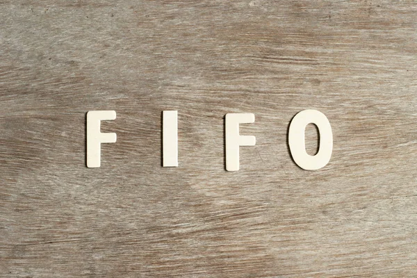 Letra del alfabeto en palabra FIFO (Abreviatura de first in first out) sobre fondo de madera — Foto de Stock